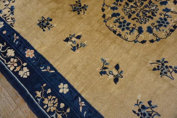 Golden beige rug featuring scattered blue floral motifs and a detailed navy blue border on wooden flooring.