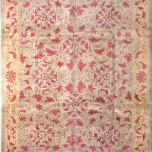 Beige and light gray rug featuring dense pink and magenta stylized floral and vine patterns with a yellow border.