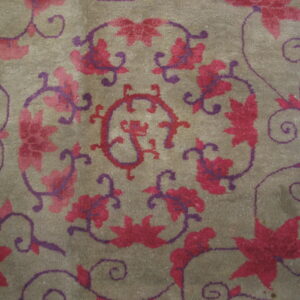 Taupe low-pile rug with a detailed swirling vine and flower pattern in magenta and deep purple.