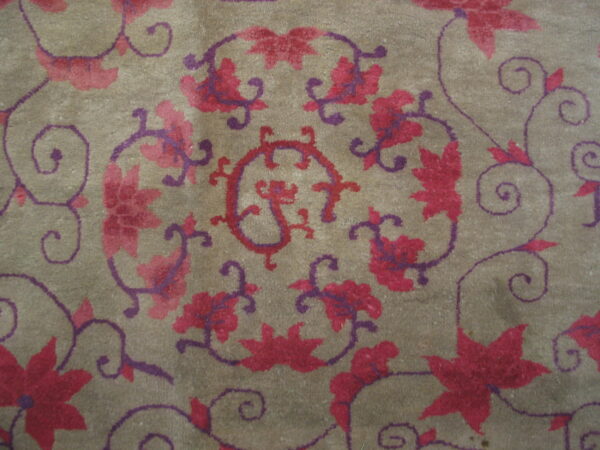 Taupe low-pile rug with a detailed swirling vine and flower pattern in magenta and deep purple.