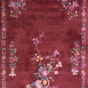 Plush maroon rug featuring elaborate pink, purple, and teal floral sprays and a continuous vine border.
