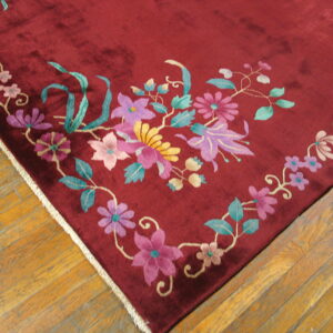 Plush burgundy rug with high-contrast pink, purple, and green floral designs on wood flooring.