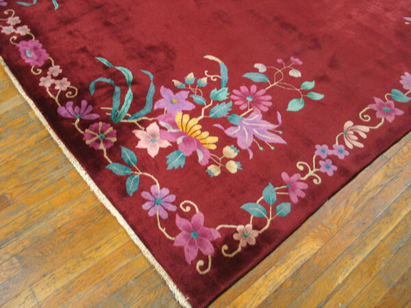 Plush burgundy rug with high-contrast pink, purple, and green floral designs on wood flooring.