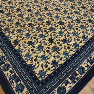 Beige rug with a dense blue cloud pattern and complex geometric borders resting on hardwood floors.