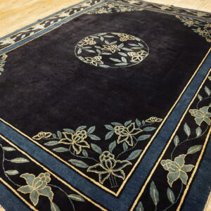 Dark blue high-pile rug with a floral medallion and borders in light blue and yellow on wood flooring.