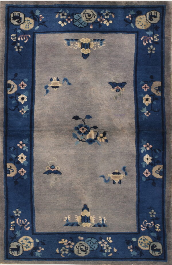 Blue-bordered rug with a gray field and scattered stylized flowers, vases, and circular medallions.