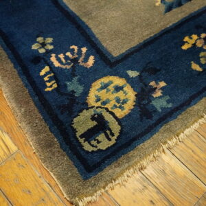 High-pile rug corner showing blue border with floral and animal motifs on yellow wood floor.