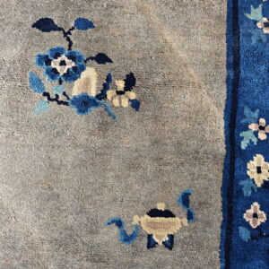 The rug's taupe field with blue flowers contrasts sharply with the vertical royal blue floral border.