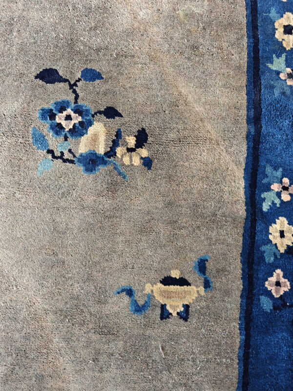 The rug's taupe field with blue flowers contrasts sharply with the vertical royal blue floral border.