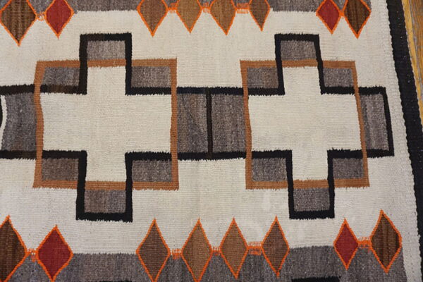 Geometric rug pattern featuring cream fields and interlocking shapes in black, brown, grey, and orange.