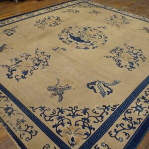 Light beige area rug with a scattered deep blue motif and detailed border on rustic hardwood flooring.