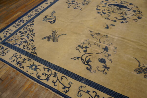 Beige rug featuring an all-over blue floral and geometric pattern on rustic wood flooring.