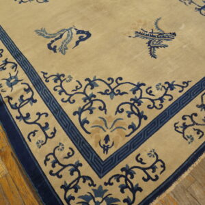 Beige rug featuring detailed indigo and light blue borders with scrolling motifs on distressed hardwood flooring.