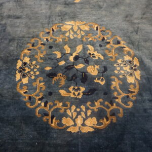 Teal high-pile rug detail showing a gold and dark blue central floral motif and scattered butterflies.