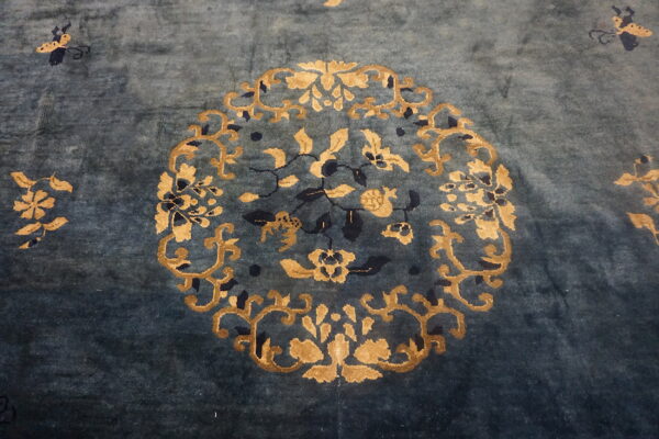 Teal high-pile rug detail showing a gold and dark blue central floral motif and scattered butterflies.