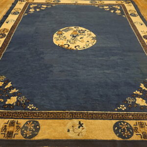 Deep blue rug with tan, ornate borders, a central medallion, and corner florals on light wood flooring.