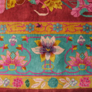 Floral pattern rug detail showing magenta field, wide teal band, and thin golden floral border.