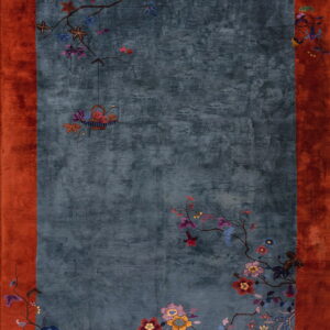 Blue rug with rust border and asymmetric floral branches and a hanging basket motif.