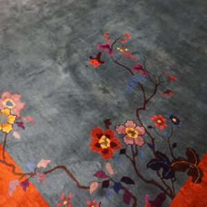 Teal high-pile rug detail showing multicolored flowers trailing from an orange border.