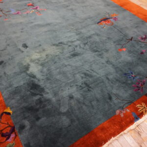 Plush teal rug with a rusty orange border and scattered colorful floral branch motifs.