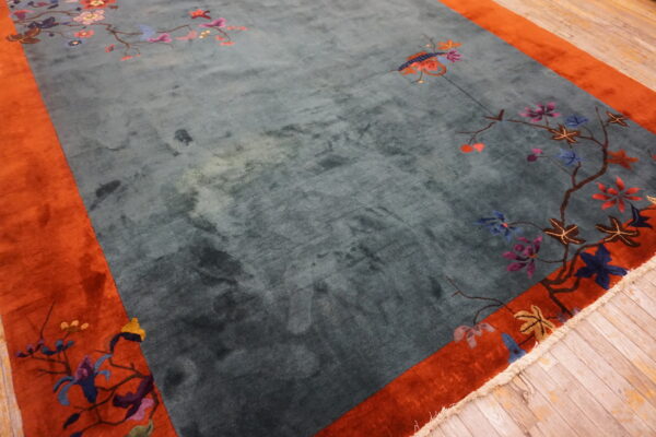 Plush teal rug with a rusty orange border and scattered colorful floral branch motifs.