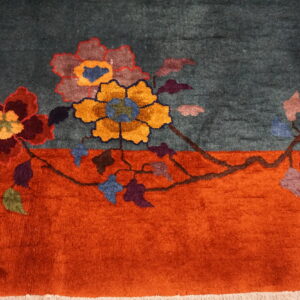 A teal rug with an orange border featuring large stylized flowers in red, gold, and purple.