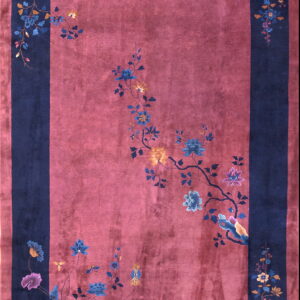 Pinkish-red rug with a navy border and blue, gold, and purple sweeping floral designs.