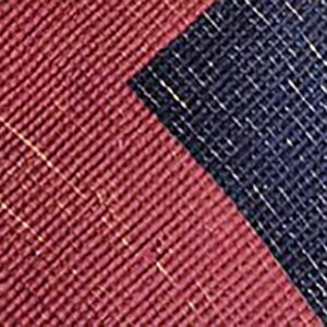 The reverse side of a rug showing woven maroon and speckled navy blue fabric blocks and a beige edge.