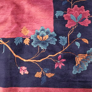 Deep-pile navy and magenta rug corner featuring carved pink, blue, and orange floral branches.