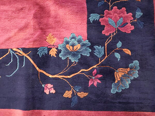 Deep-pile navy and magenta rug corner featuring carved pink, blue, and orange floral branches.