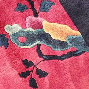 Highly textured rug detail showing a pink field and sculpted branches with colorful abstract forms.