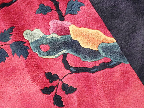Highly textured rug detail showing a pink field and sculpted branches with colorful abstract forms.