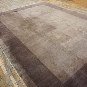 Large rectangular rug featuring a taupe field and wide stepped borders of deep brown on rustic wood floors.