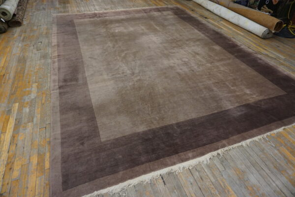Shading taupe rug features two concentric borders of darker brown on distressed wooden floors.