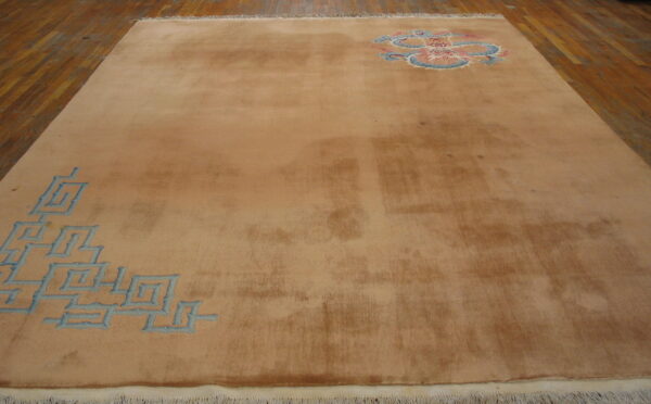 Camel-colored rug with blue geometric and multicolored dragon motifs rests on polished wood floor.