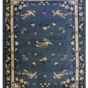 Dark blue rug with stylized gold birds and scattered floral elements inside a cream and dark blue border.