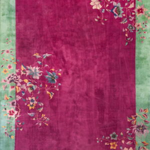 Magenta rug with a wide mint green border and multicolored cascading floral vine designs.