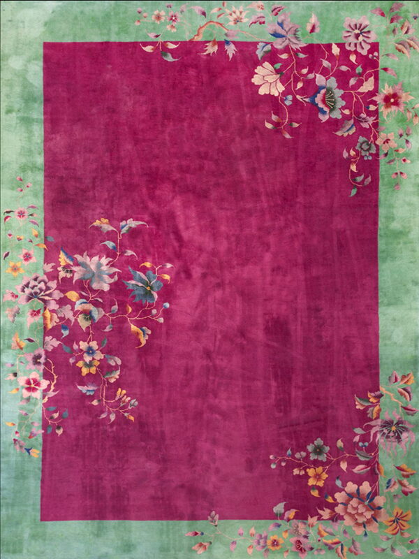 Magenta rug with a wide mint green border and multicolored cascading floral vine designs.