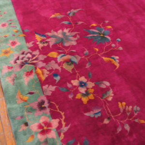 High-pile magenta and green rug featuring large pink, blue, and yellow floral patterns on wood floors.