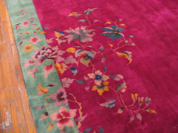 High-pile magenta and green rug featuring large pink, blue, and yellow floral patterns on wood floors.