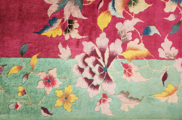 Textured rug features large multicolored floral patterns separating a magenta field from a seafoam green field.