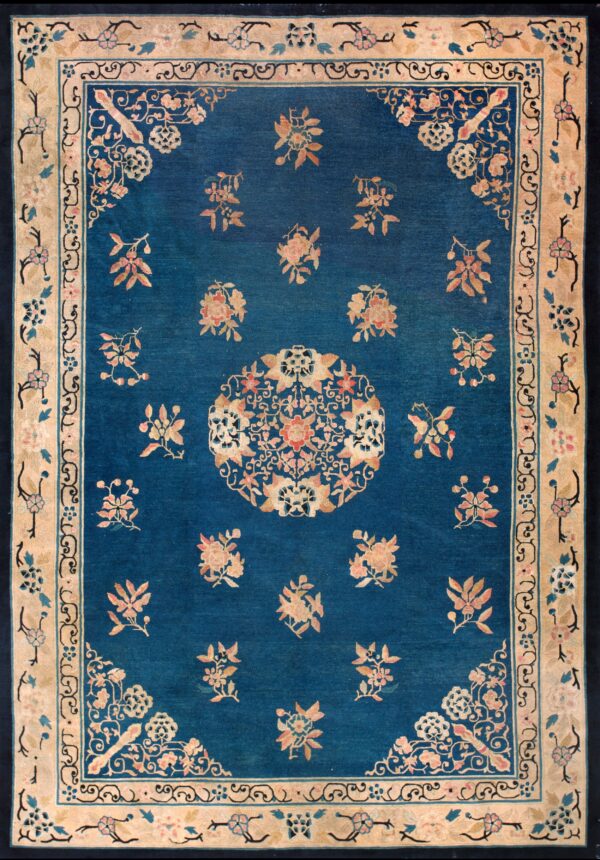 Blue rug with a tan border and scattered pink and gold floral patterns and a detailed central medallion.