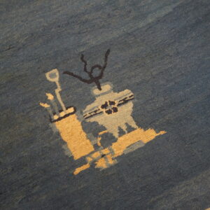 Close-up of a dense, plush blue rug featuring abstract shapes in tan, light blue, and black.