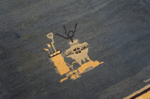 Close-up of a dense, plush blue rug featuring abstract shapes in tan, light blue, and black.