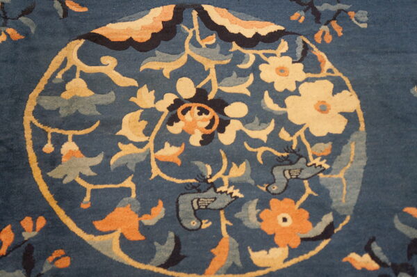 Ornate deep blue rug featuring a circular gold medallion with cream flowers, apricot accents, and stylized blue birds.