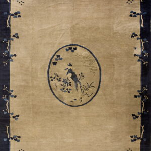 Beige rug featuring a dark blue bird medallion and trailing floral branches on a thick navy border.