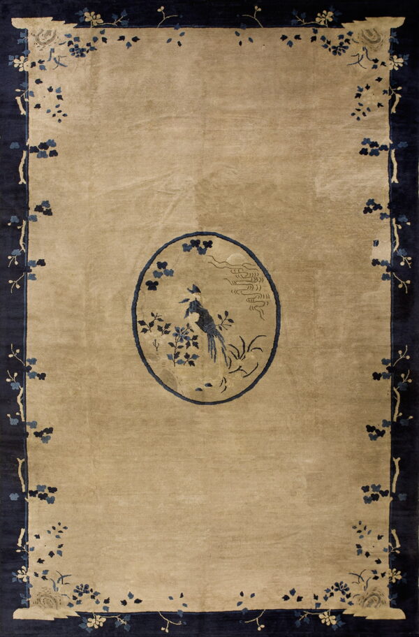 Beige rug featuring a dark blue bird medallion and trailing floral branches on a thick navy border.