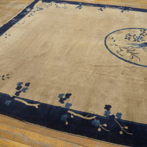 Beige rug featuring a navy blue border with stylized branches and a blue central bird design.