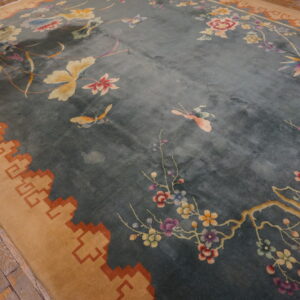 Plush blue rug featuring colorful butterflies, cherry blossoms, and a stepped tan border on wood flooring.