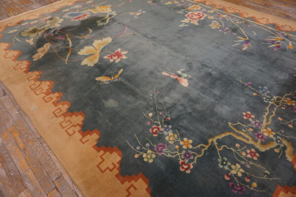 Plush blue rug featuring colorful butterflies, cherry blossoms, and a stepped tan border on wood flooring.